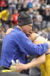 Steve McKee, left, embraces his son, Mitch, after the 120-pound State 3A individual title match. Steve, battling cancer, had to leave the hospital to watch the event. (Photo by John Millea, MSHSL.org)