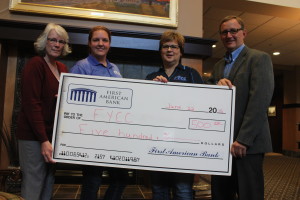 Lori Gelting (far left) and Dennis Martodam (far right) of First American Bank present a check to Nicole Rice and Sandra Greninger of FYCC. 