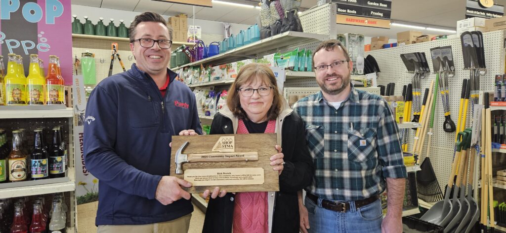 Members of the Petrich family - sons Chris and Justin, along with Rick's wife, Pat - accept the Shop STMA Community Impact Award on Rick's behalf. Rick died of cancer earlier in 2024.