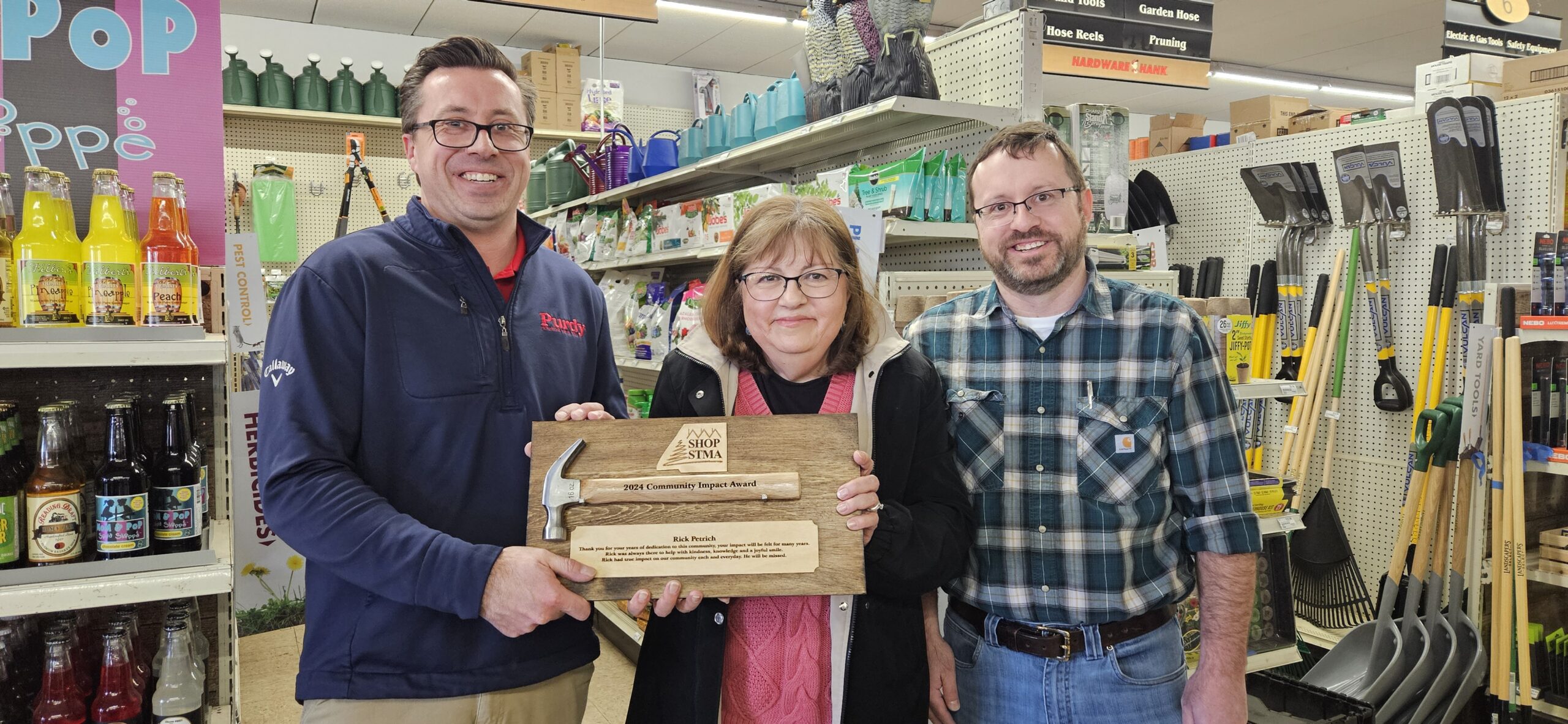 Members of the Petrich family - sons Chris and Justin, along with Rick's wife, Pat - accept the Shop STMA Community Impact Award on Rick's behalf. Rick died of cancer earlier in 2024. 